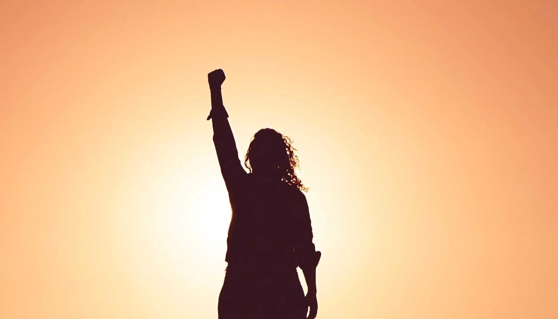 A software engineer in the sunlight raising their fist to the sky in sign of victory