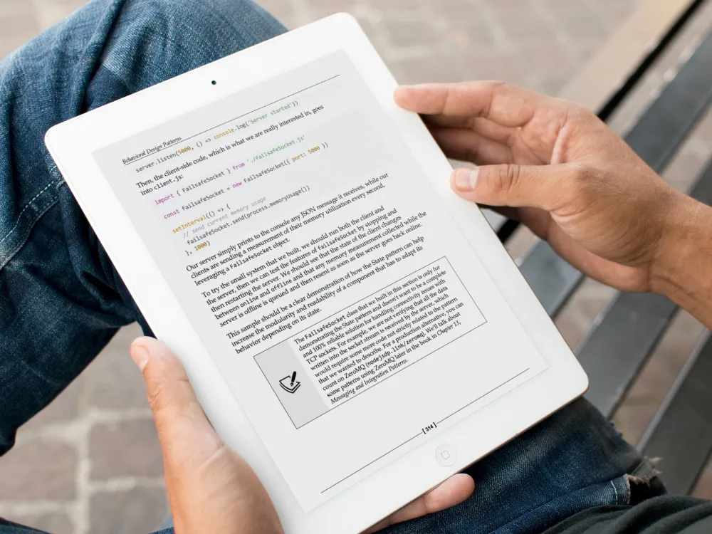Hands holding a tablet showing a page from Node.js Design Patterns, with highlighted code examples visible.